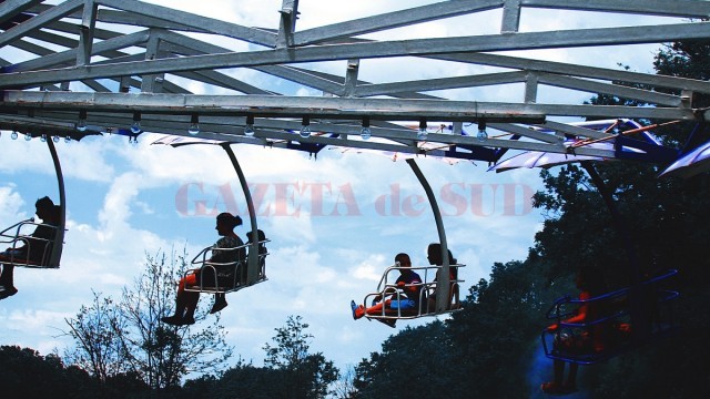 Siluete de oameni se conturează pe fundalul cerului, iar timpul parcă stă în loc sub umbrelele metalice.