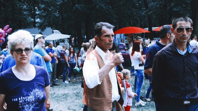 Oamenii privesc concertul de muzică populară, cu cântece despre dragoste, familie, bani și băutură