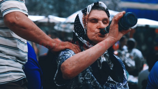 O bătrână savurează o sticlă de bere, în timp ce soțul ei pleacă să cumpere mâncare