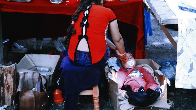 O altă fetiță are grijă de fratele ei mic, ascuns de vizitatori într-o cutie de carton
