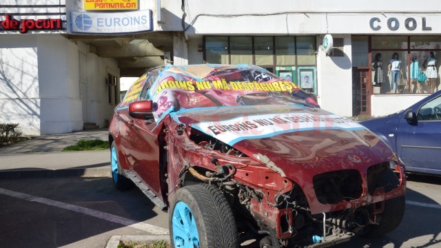 Clienta firmei de asigurări Euroins, a cărei mașină a fost avariată în accident, a protestat punându-și mașina în fața sediului din Craiova al asigurătorului, pe motiv că nici după două luni de la accident nu i s-a comunicat valoarea de despăgubire (Foto: Lucian Anghel)