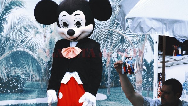 Un alt bărbat ține în mână o fotografie a faimosului Mickey Mouse, pentru a atrage potențiali clienți.