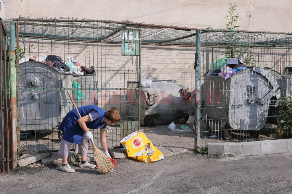 Femeia de serviciu strânge de mai multe ori gunoiul de pe lângă tomberoane (Foto: Lucian Anghel)