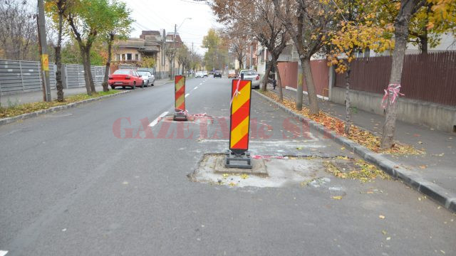 Pe strada Rovine au rămas gropi din cauză că gurile de canal şi capacele conductelor de gaze nu au fost aduse la nivelul asfaltului (FOTO: Claudiu Tudor)