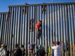 Imigranți sărind gardul în zona Tijuana, în statul mexican Baja California. Locul este preferat și de traficanții români care, împreună cu cei mexicani, reușesc să treagă ilegal mii de români peste graniță în SUA. FOTO: EPA