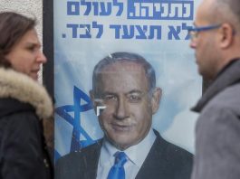 Oamenii se uită la un afiș al premierului şi liderului partidului Likud, Benjamin Netanyahu (Foto: Ariel Schalit)