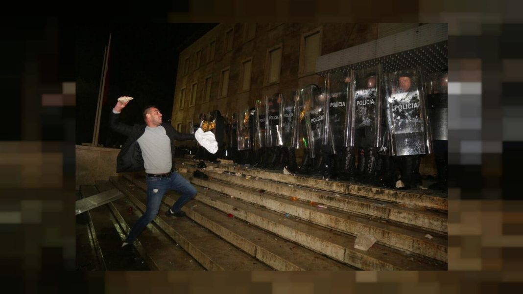 Un protestatar aruncă cu pietre în polițiștii din fața biroului primului ministru în timpul ciocnirilor din Tirana, Albania