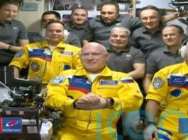 Trei cosmonauți ruși, îmbrăcați în culorile Ucrainei