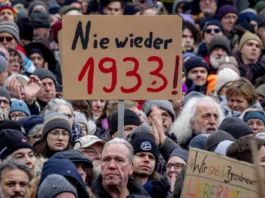 Oamenii se adună în timp ce protestează împotriva partidului AfD și a extremismului de dreapta la Frankfurt/Main, Germania, sâmbătă, 20 ianuarie 2024. Semnul scrie „Niciodată 1933”. (AP Photo/Michael Probst)