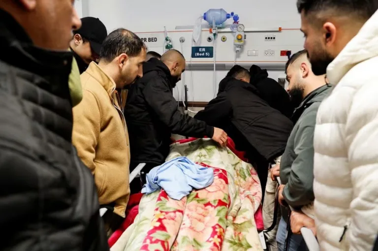 Cei îndoliați se află lângă cadavrul unui palestinian ucis în urma unui raid israelian, într-un spital din Jenin, în Cisiordania ocupată de Israel, 30 ianuarie 2024. (FOTO: REUTERS/Raneen Sawafta)