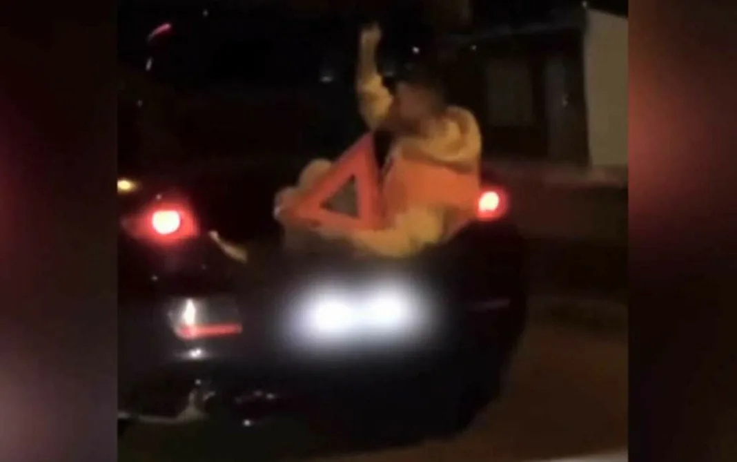Tânăr filmat în portbagajul unei maşini, cu un triunghi reflectorizant în mână