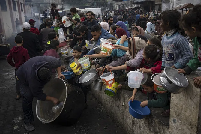 Palestinienii se aliniază pentru o masă gratuită în Rafah, Fâșia Gaza, joi, 21 decembrie 2023. Agențiile internaționale de ajutor spun că Gaza suferă de lipsă de alimente, medicamente și alte provizii de bază ca urmare a războiului de două luni și jumătate dintre Israel și Hamas. (Foto AP/Fatima Shbair)