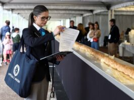 Joanne Brent, arbitra Guinness World Records, stă lângă baghetă în timpul inspecției pentru cea mai lungă baghetă în timpul spectacolului de baghete din Suresnes, lângă Paris, Franța, 5 mai 2024. (REUTERS/Stephanie Lecocq)