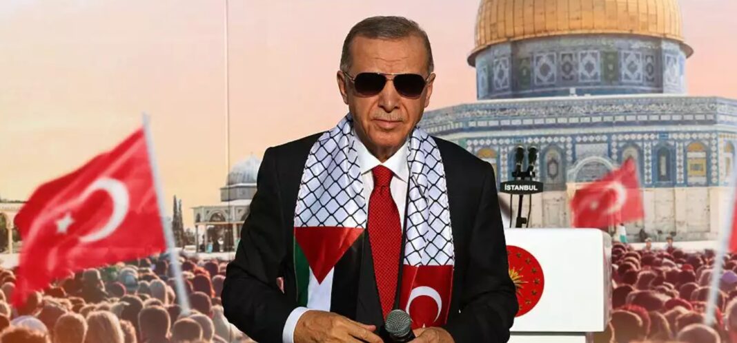 Președintele turc Tayyip Erdogan, purtând o eșarfă cu steagul palestinian și turcesc, stă pe scenă în timpul unui miting organizat de partidul AKP în solidaritate cu palestinienii din Gaza, la Istanbul