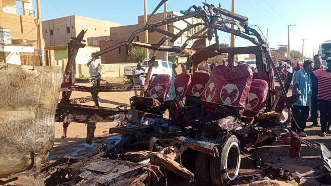 Oamenii se adună lângă un vehicul distrus, în urma bombardamentelor din partea Forțelor de Sprijin Rapid, în Omdurman, Sudan, 10 decembrie 2024