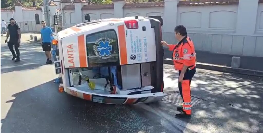 Ambulanță răsturnată în misiune după coliziunea cu un autoturism