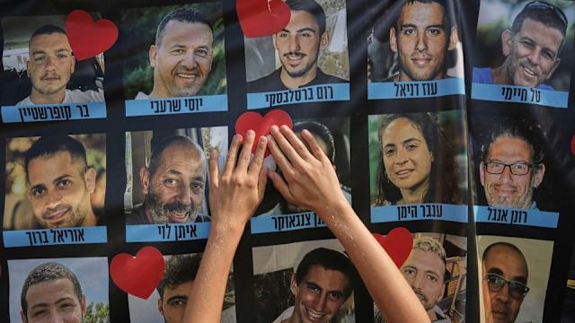 O persoană lipește un autocolant în formă de inimă pe un banner cu imagini ale ostaticilor israelieni în timpul unei adunări în Piața Ostaticilor din Tel Aviv, Israel, luni (Oded Balilty/AP)