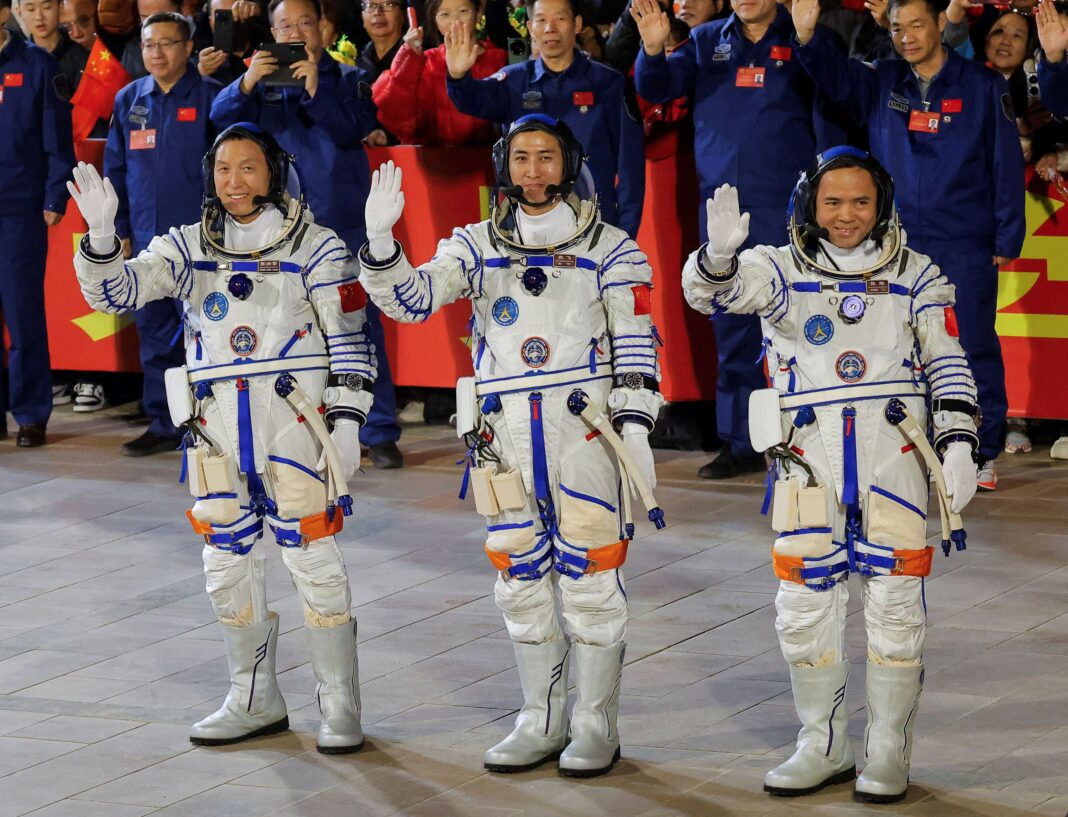 Astronauții Zhang Hongzhang, Wu Fei și Zhang Lu își salută echipa în timpul unei ceremonii de despărțire înainte de a participa la misiunea spațială Shenzhou-21