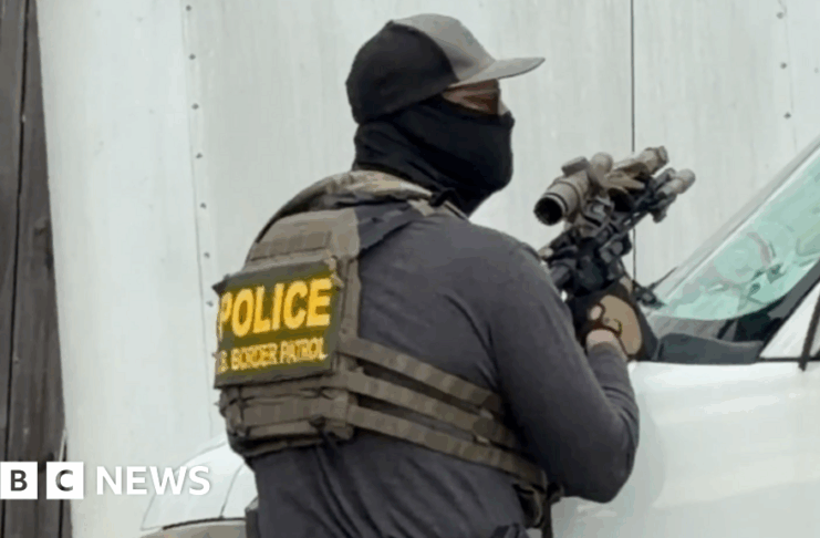 Un agent CBP care ține o pușcă cu lunetă o îndreaptă spre un acoperiș în timpul unei arestări recente în New Orleans