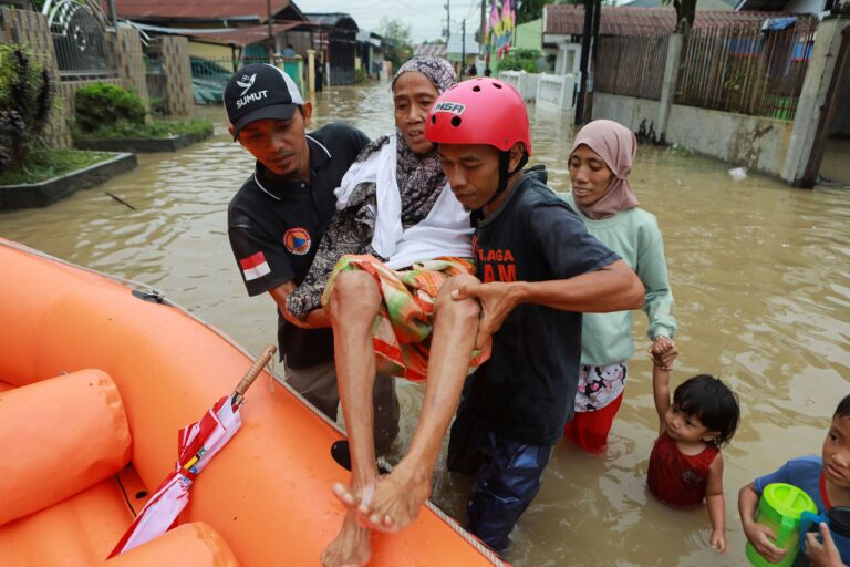 Salvatorii evacuează o femeie în vârstă dintr-o zonă inundată de ploi abundente în Deli Serdang, provincia Sumatra de Nord, Indonezia