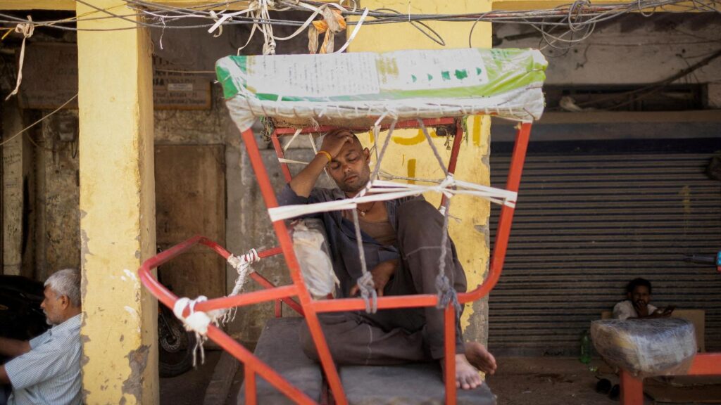 Un bărbat se odihnește în ricșa sa într-o după-amiază fierbinte de vară din Delhi