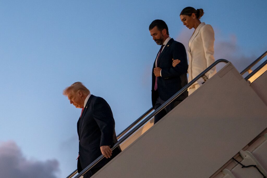 Președintele Donald Trump coboară din Air Force One împreună cu fiul său, Donald Trump Jr., și Bettina Anderson, la sosirea pe Aeroportul Internațional Palm Beach pe 27 martie în West Palm Beach, Florida)Nathan Howard/Getty Images )