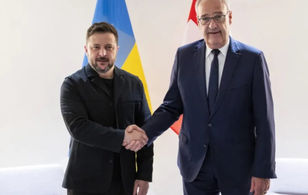 Președintele Elveției, Guy Parmelin, dă mâna cu președintele Ucrainei, Volodimir Zelenski, pe aeroportul din Geneva, pe 15 iunie 2026